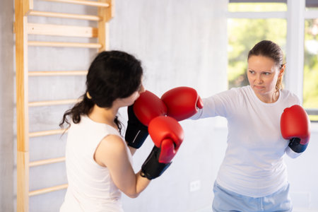 Focused woman practicing boxing punches in sparring during group self defence courseの写真素材