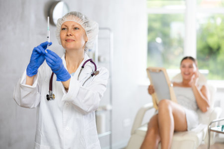 Doctor in disposable cap examine integrity of syringe with drug before manipulationsの写真素材