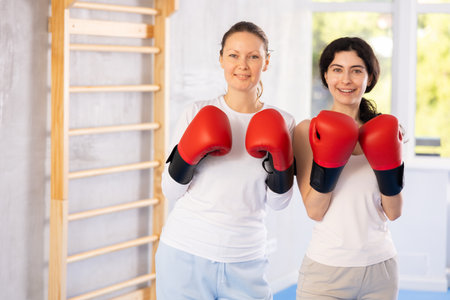 Focused woman practicing boxing punches in sparring during group self defence courseの写真素材