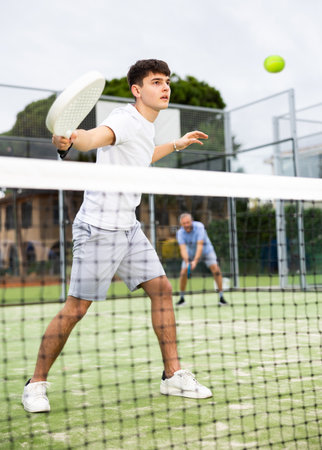 Sporty young guy playing padel on open courtの写真素材
