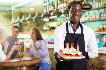 View on the African adult man holding pinchos at a barの写真素材