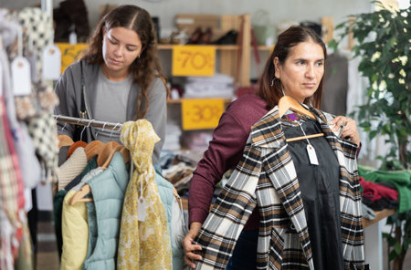 Selective Latina woman choosing something for autumn-winter in clothing storeの写真素材