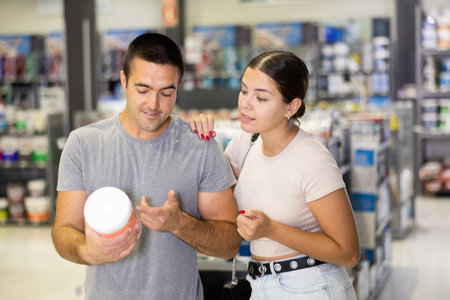 Husband buyer with paint container in hand consults with wife and examines can of enamel dyeの写真素材