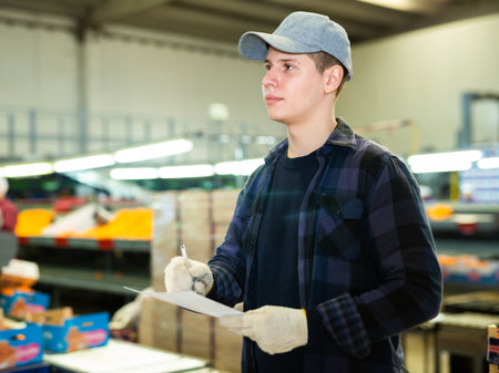 Positive male worker fills out a document at a citrus processing plant.の写真素材