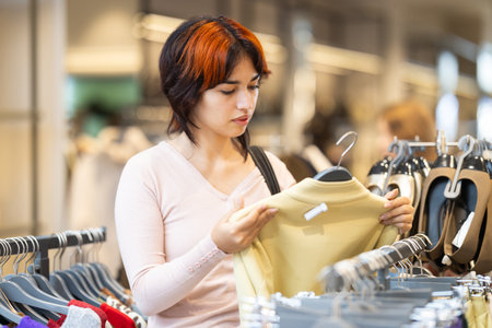 Young woman search and choose sweaterの写真素材