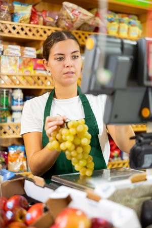 Young saleswoman weighs grapes on a scaleの写真素材