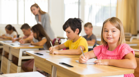 Smiling diligent preteen girl studying with classmates in schoolの写真素材