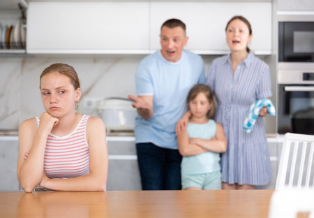 Parents scolding teenager daughter in kitchenの写真素材