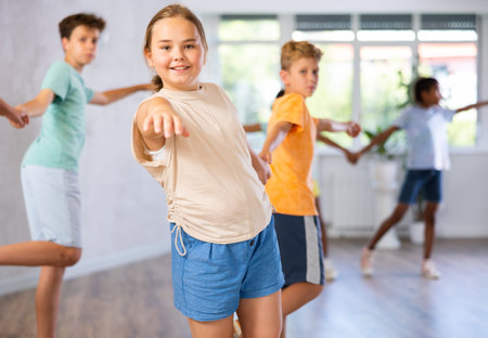 Light-skinned boy and girl dance in pairs and rehearse dance before performing on main floor.