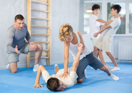 Diligent preteen student twisting his partner's arm on the floor