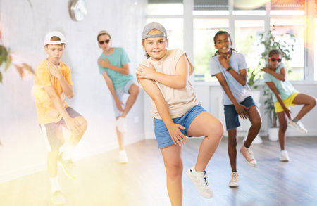 Multiethnic group of children in casual wear training hip hop movements in dance studio