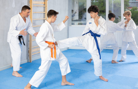 Diligent preteen attendee of karate classes fighting with his opponent in sports hallの写真素材
