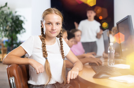 Smiling girl sitting at computer table in training roomの写真素材