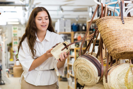 Young woman choosing straw bag at storeの写真素材