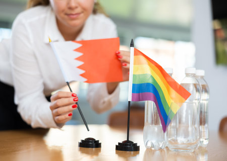 Young woman putting Bahrain flag on table in officeの写真素材