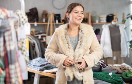 Young woman trying on fur coat in store