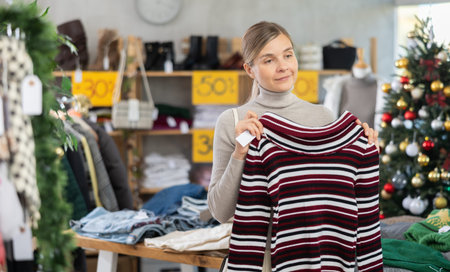 Woman standing in sale area and choosing a sweater