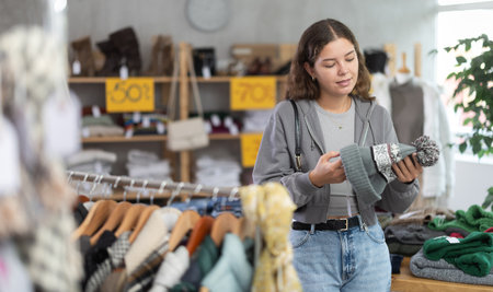 Happy girl chooses hat in modern clothing storeの写真素材