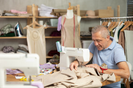 Mature man tailor sewing in workshopの写真素材