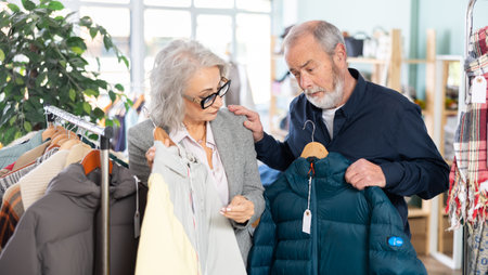 Elderly couple choosing a warm down jacket togetherの写真素材