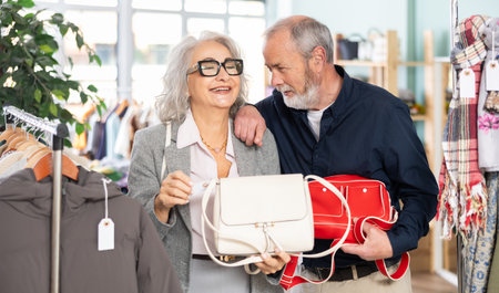 Elderly couple chooses fashionable handbag in clothing storeの写真素材
