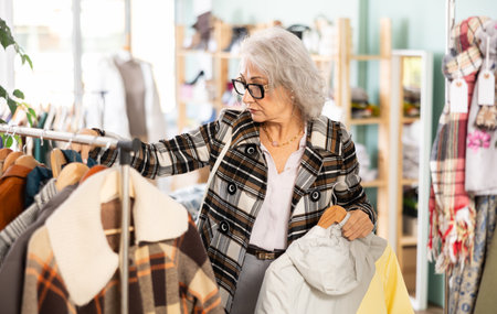 Family clothing store, senior woman customer chooses jacket or coatの写真素材
