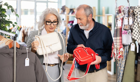 Mature couple spend time in shop and choose handbagの写真素材