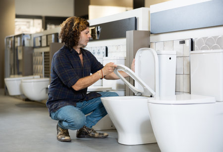 in plumbing department, male buyer checks for defects of toilet before purchasing toilet panの写真素材