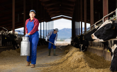 Young woman farmer with can works on dairy farmの写真素材