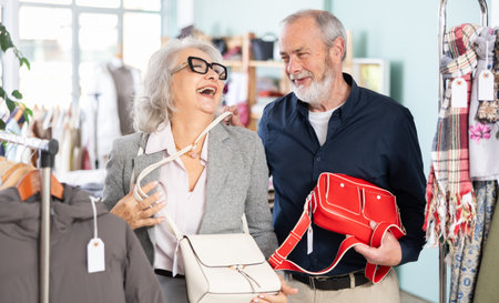 Mature couple spend time in shop and choose handbagの写真素材