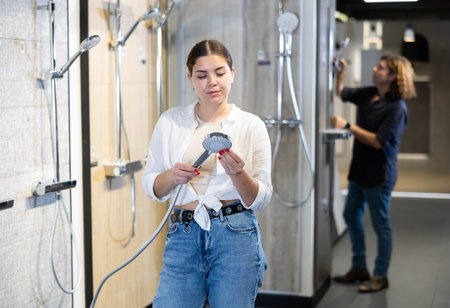 in plumbing department,woman examines shower head and quality of metal coating.の写真素材