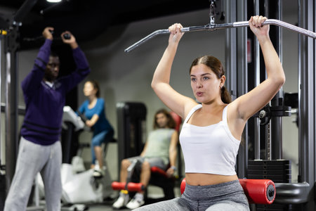 Caucasian woman doing reps on lat pull down machine in gymの写真素材