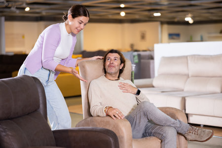 couple chooses comfortable armchair in furniture storeの写真素材