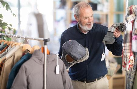 Elderly man chooses warm hat in clothing storeの写真素材