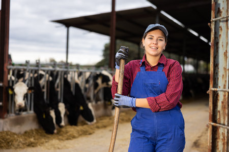 Farmer woman stands with rake at cow farmの写真素材
