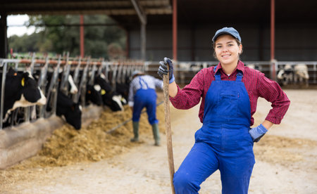 Farmer woman stands with rake at cow farmの写真素材