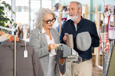 Elderly husband and wife chooses warm hat in clothing storeの写真素材