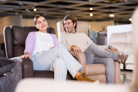 couple chooses comfortable armchair in furniture storeの写真素材