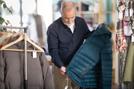Family clothing store, senior man customer choose down jacketの写真素材