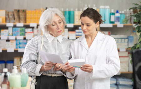Mature woman consults pharmacist in pharmacyの写真素材