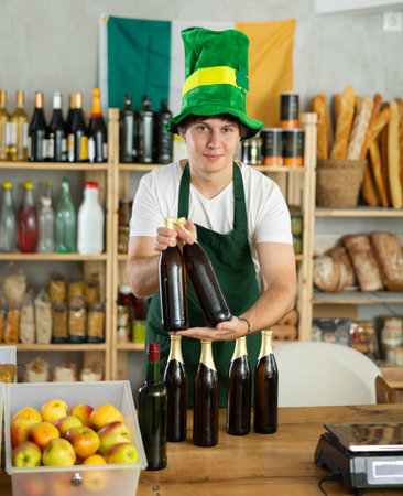 Smiling man seller in traditional Irish green cap offers Irish ale on St. Patrick Day in supermarket