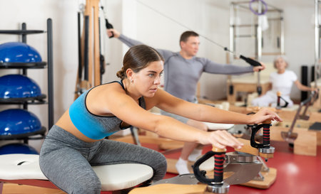 Young girl during Pilates training performs exercises and tasks on heron pulley tower
