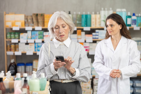 elderly woman stands in a pharmacy against the background of a pharmacistの写真素材