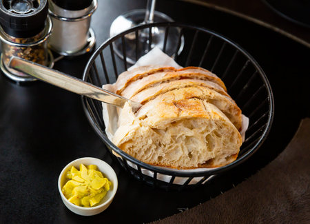 Sliced fresh baked artisan bread with butter in serving basket