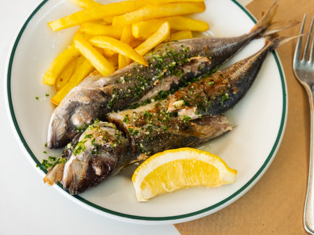 Grilled mackerels with French fries, lemon and sauce