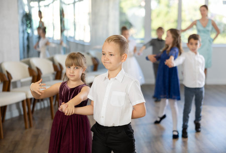 Enthusiastic preteen children dancing waltz in pairs in dance school
