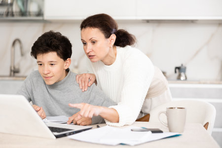 Boy studiyng, mother helpingの写真素材