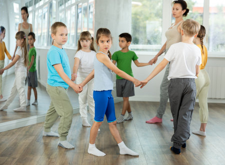 Children holding hands and dancing in round dance in choreography classの写真素材