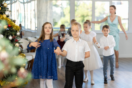 Preteen children in elegant outfits practicing partner dance in Christmas studioの写真素材
