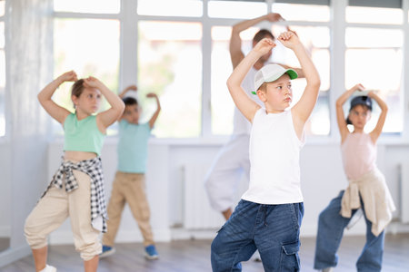 Young happy boy and group of positive children practicing energetic hip hop movements at dance schoolの写真素材